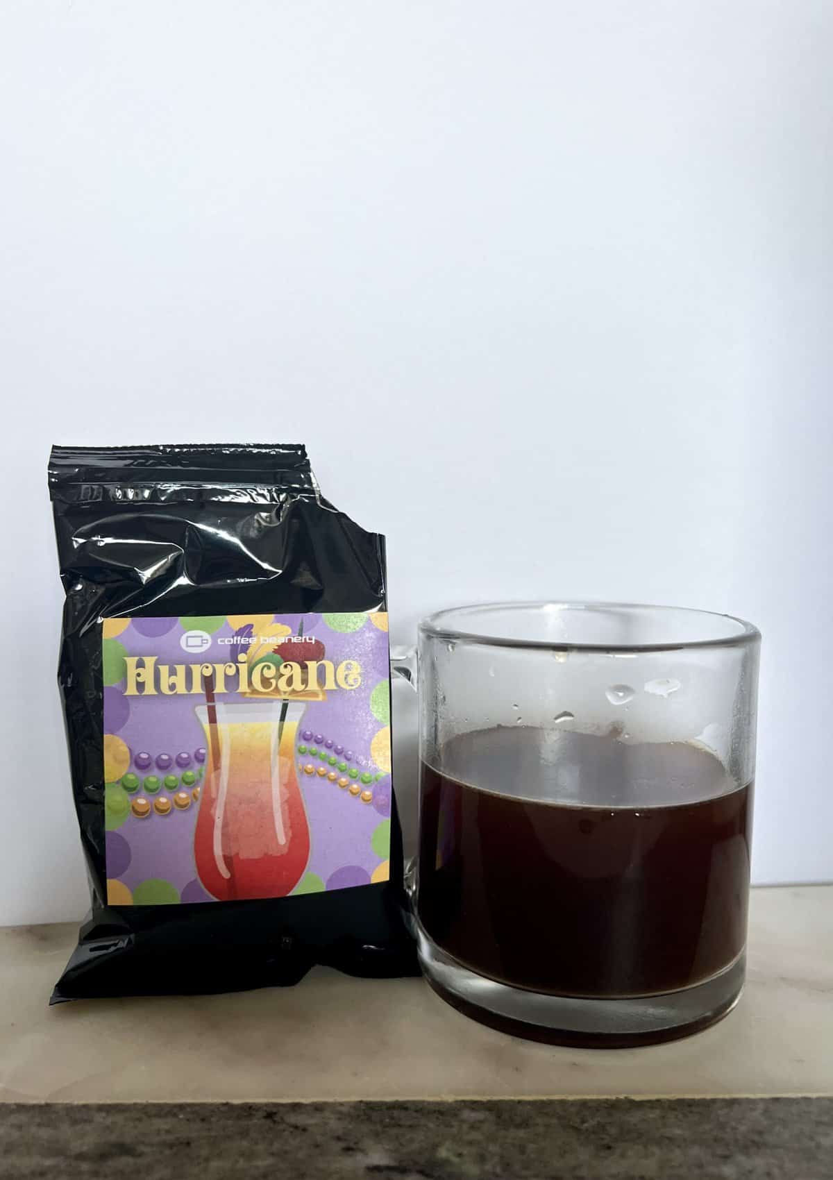 open-package-of-coffee-beanery-Hurricane-next-to-a-cup-of-brewed-coffee-scaled